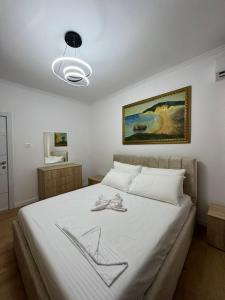 ein Schlafzimmer mit einem Bett mit weißer Bettwäsche und einem Gemälde in der Unterkunft Vila Ademi Ksamil in Ksamil