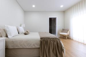 une chambre blanche avec un grand lit et une chaise dans l'établissement Casa da Cruz Alta, à Seia 18 autres photos