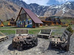 a barn with a pile of logs in front of it with mountains at Kuro Kazbegi • ყურო ყაზბეგი in Kazbegi