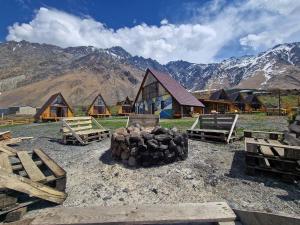 a group of wooden buildings with mountains in the background at Kuro Kazbegi • ყურო ყაზბეგი in Kazbegi