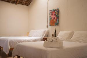 2 camas con toallas en una habitación en Hotel Perro Surfero Todos Santos, en Todos Santos