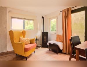 a living room with a yellow chair and a bed at Chalet De Maanvaren in Hattemerbroek