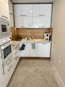 een witte keuken met een spoelbak en een magnetron bij Pool apartment on the beach in Boergas