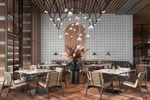 a dining room with tables and chairs and a chandelier at Flow and Co. Qingdao, Autograph Collection in Qingdao