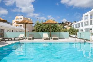 einen Pool in einem Hotel mit Stühlen und Sonnenschirmen in der Unterkunft Alkithea luxury suites in Karpathos