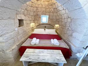 1 dormitorio con 1 cama en una pared de piedra en Trullo fiore en Ostuni