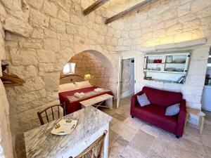 a living room with a bed and a red chair at Trullo fiore in Ostuni