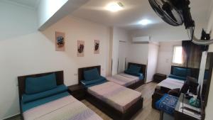 um quarto com três camas e um sofá em فندق أجياد Agyad Hotel em Assiut