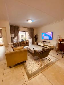 ein Wohnzimmer mit einem Sofa und einem TV in der Unterkunft Stunning 3Bed 2bath Oasis W King Bed in Midrand