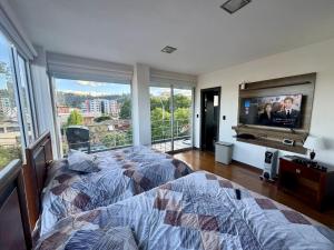 Schlafzimmer mit einem Bett und einem Flachbild-TV in der Unterkunft Maravilloso departamento con moto electricá in Cuenca