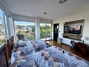 a bedroom with a bed and a flat screen tv at Maravilloso departamento con moto electricá in Cuenca +10 photos