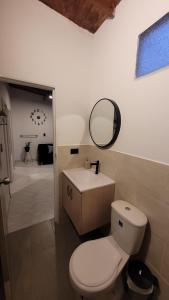 a bathroom with a toilet and a mirror and a sink at La Familia Hostel - Manila in Medellín