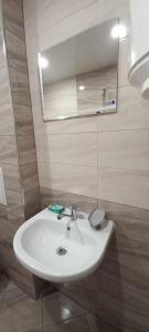 La salle de bains est pourvue d'un lavabo blanc et d'un miroir. dans l'établissement Апартамент-идеален център Ямбол, à Yambol