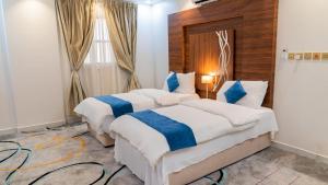 Dos camas en una habitación de hotel con azul y blanco en فندق زائر الشمال en Hail