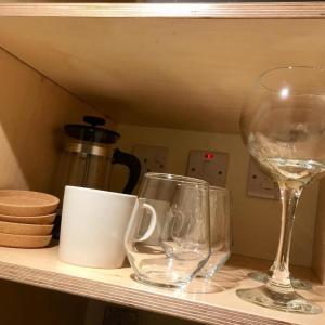 dos copas de vino y tazas en un estante en Thornfield Farm Luxury Glamping Pods, The Dark Hedges, Ballycastle en Stranocum