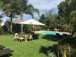 a table with an umbrella and chairs next to a pool at Albourne Guesthouse in Somerset West