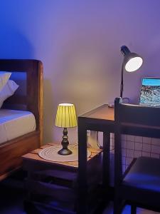 een slaapkamer met een bureau met een lamp en een bed bij Dahari Home Hostel in Moshi