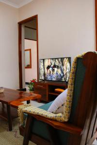 een woonkamer met een televisie, een tafel en een stoel bij Dahari Home Hostel in Moshi