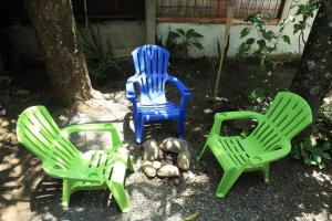 three plastic lawn chairs sitting next to a tree at Cabaña Viento - RiverBeach in Jacó