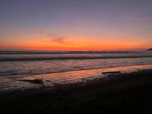 una puesta de sol en una playa con el océano en Cabaña Viento - RiverBeach, en Jacó