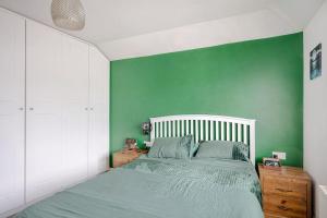 A Spacious 2 Bed Home in a Central Location في بيشوبس ستورتفورد: غرفة نوم خضراء بسرير وجدار أخضر