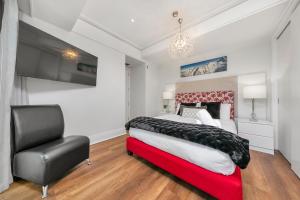 a bedroom with a large bed and a chair at The Charming Cracker! in Auckland