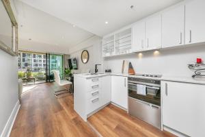 a kitchen with white cabinets and a large window at The Charming Cracker! in Auckland