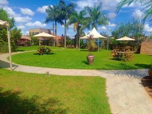 un parc avec des tables de pique-nique et des parasols sur l'herbe dans l'établissement Perla Hotel, à Kampala