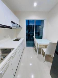 a white kitchen with a table and a dining room at Vacation pool condo in Ban Rangeng