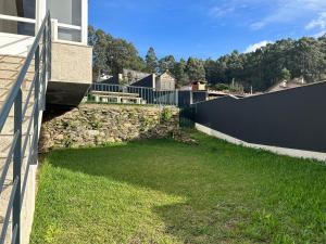 een grasveld naast een muur met een hek bij Villabembrive in Vigo