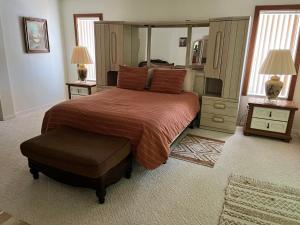 a bedroom with a large bed and a ottoman at Grandma’s White House in Palm Coast