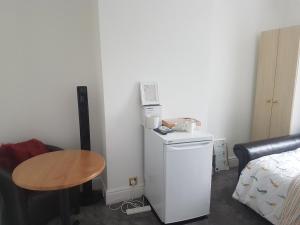 um pequeno quarto com uma pequena mesa e um pequeno frigorífico em A Quiet & Comfortable 4 Bedroom house em Manchester