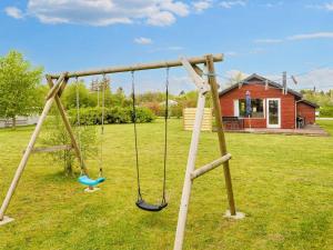 a swing set in a yard with a house at 6 person holiday home in Nibe in Nibe