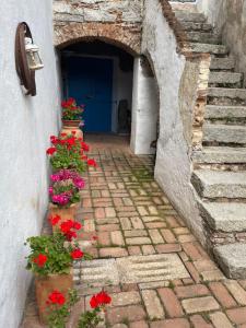 an alley with red flowers and a blue door at B&B Corte San Lussorio in Oliena