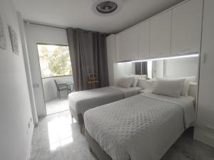 two beds in a hotel room with a window at Vivienda Agaete Parque in Playa del Ingles