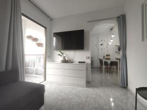 ein weißes Wohnzimmer mit einem TV und einem Tisch in der Unterkunft Vivienda Agaete Parque in Playa del Ingles