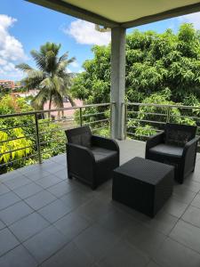dwa krzesła i stół na balkonie z palmą w obiekcie Belle Luxury Apartments w mieście Gros Islet