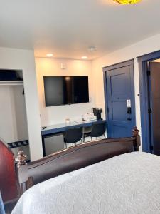 a bedroom with a bed and a desk with a television at Werner Room 204, Hyland Hotel in Palmer
