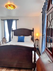 a bedroom with a wooden bed with a blue curtain at Werner Room 204, Hyland Hotel in Palmer