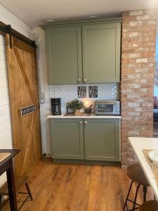 una cocina con armarios verdes y una pared de ladrillo en We put the ‘Fun’ in your stay!, en Walla Walla