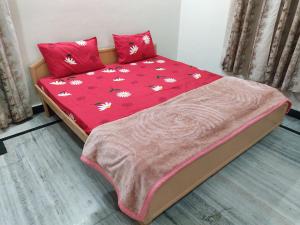 a bed with a red comforter with flowers on it at Nature's Paradise Homestay in Haridwār