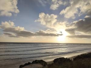 a view of the ocean from a beach with the sunset at beach house in Venus Bay