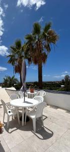 einen weißen Tisch mit Stühlen und eine Palme in der Unterkunft VISION RELAX HOME in Playa del Ingles