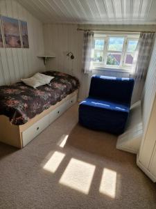 um quarto com uma cama e uma cadeira azul em Idyllisk feriested em Røyksund