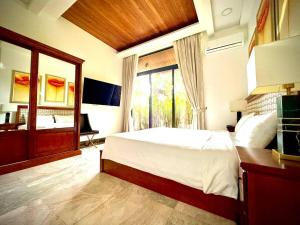 a bedroom with a bed and a bathroom with a window at Villa 7 bedrooms in Ban Mai Salae