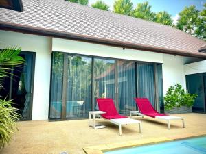 two red chairs sitting on a patio next to a pool at Villa 7 bedrooms in Ban Mai Salae