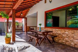 a patio with a wooden table and benches at Bella casa da paz in Búzios