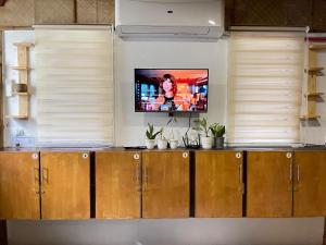 een keuken met een televisie aan een muur met ramen bij Galera Lodge in Puerto Galera