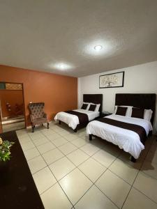 a hotel room with two beds and a chair at Hotel & Balneario Los Angeles in Taxco de Alarcón