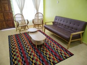 - un salon avec un canapé, des chaises et un tapis dans l'établissement Sobey Laris Homestay QASEH, à Pasir Mas